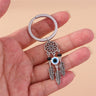 Center eye feather keychain held in a hand, showing the white eye bead, black side beads and open flower circle.