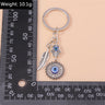 Hamsa medallion and feather keychain beside an L-shaped ruler, with a weight label above.