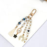 White and black evil eye keychain with a horseshoe charm, heart motif bead and cream tassel, arranged diagonally