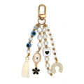 White and black beaded keychain with a horseshoe charm, oval eye pendant, black flower, heart motif bead and cream tassel