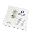White evil eye keychain charm with a light blue ring, dark center and silver tone lobster clasp on a card against a white background.