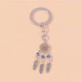 Three blue beads and three silver tone feathers below an open flower circle, attached to a key ring by a short chain.