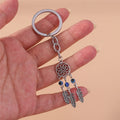 Three bead feather keychain held in a hand, with a short chain, open flower circle and three blue bead strands.
