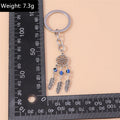 Three bead feather keychain beside an L-shaped ruler, with a weight label in the upper left corner.
