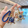 Blue and white turtle evil eye keychains held side by side, with braided loops and gold tone patterned shells.