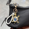 White turtle evil eye keychain clipped to a black handbag, with a braided loop and clear shell accents.