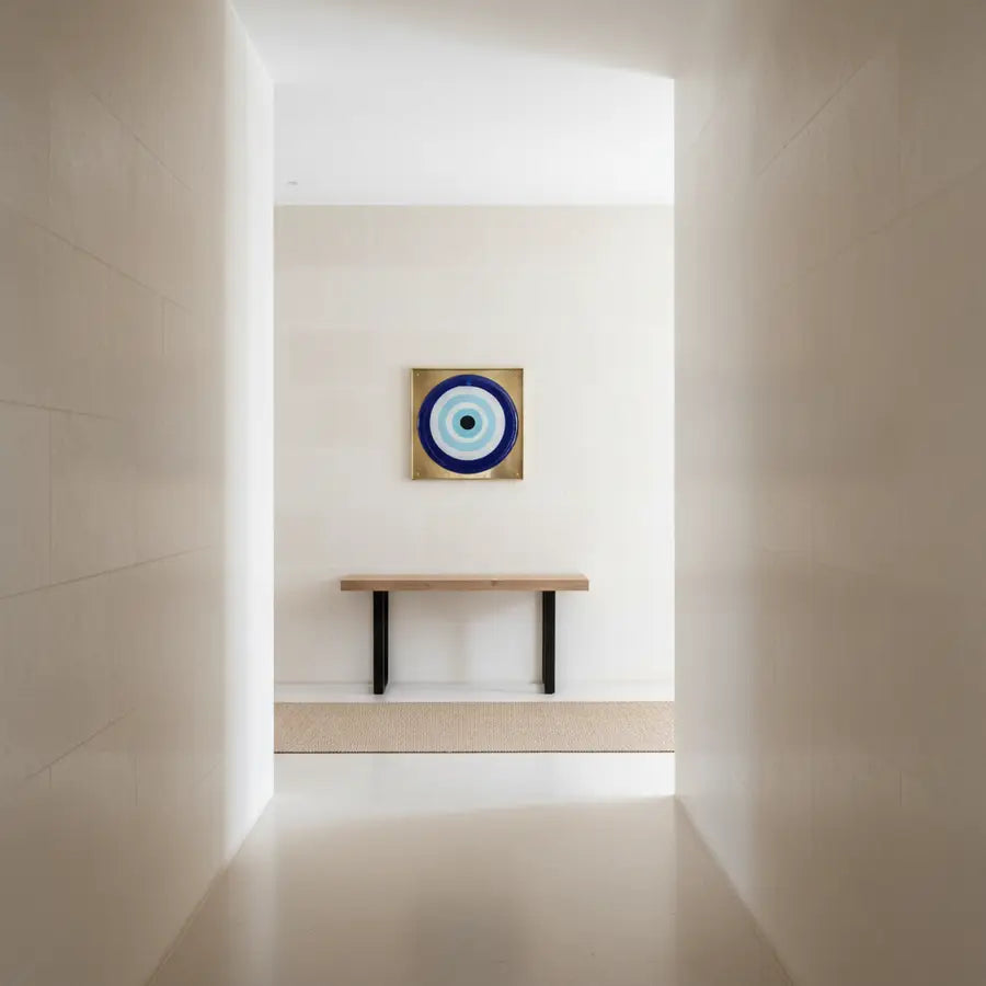 Modern neutral hallway with a single evil eye wall hanging above a narrow console