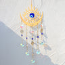Gold tone eye and crescent suncatcher with a blue eye center, blue beads and five round faceted drops.