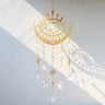 Gold tone eye and crescent suncatcher with a clear faceted center, small eye charms and five round drops.