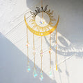 Gold tone sun and crescent suncatcher with faceted accents along five chains and pointed drops.