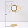 Gold tone eye tabletop mirror beside a vertical measurement line labeled 25 cm