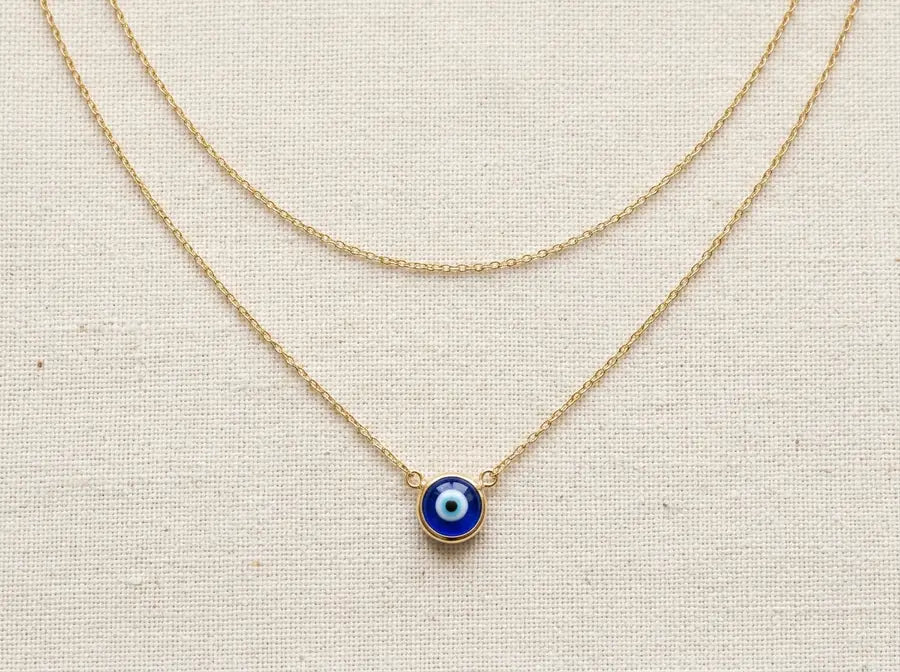 Two gold evil eye layers with a visible empty two-inch gap between the upper chain and the lower blue eye pendant