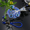 Close-up of blue eye motifs, silver tone branches and a blue hanging loop
