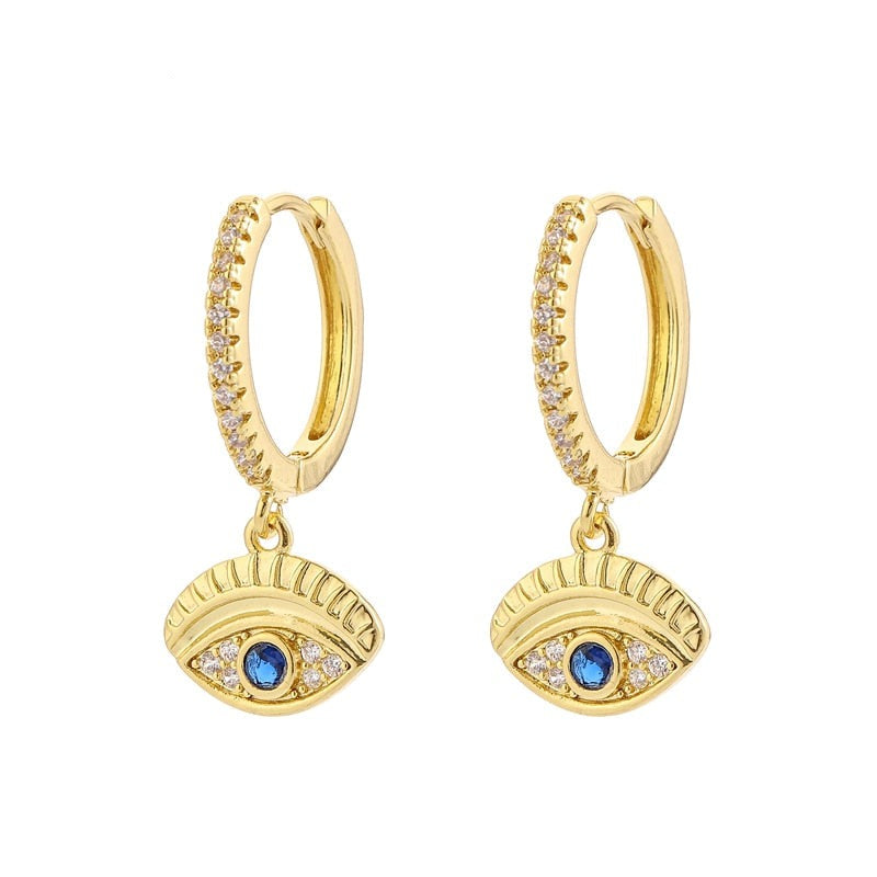 Gold tone hoops with clear accents and horizontal blue evil eye charms with grooved lash details