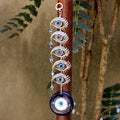 Blue evil eye hanging with five silver tone eye motifs, displayed against a brown post
