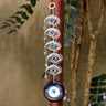 Blue evil eye hanging with five silver tone eye motifs, displayed against a brown post